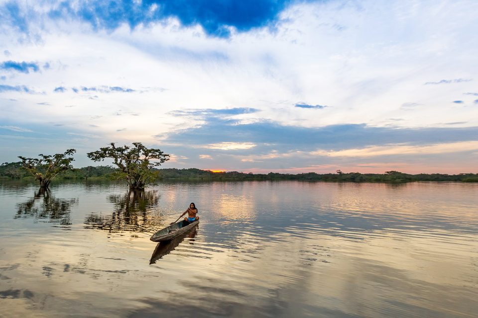 A man canoeing on the river at sunrise