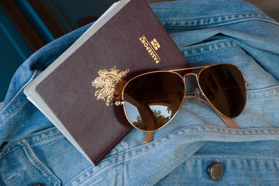 Passport and sunglasses on a denim jacket