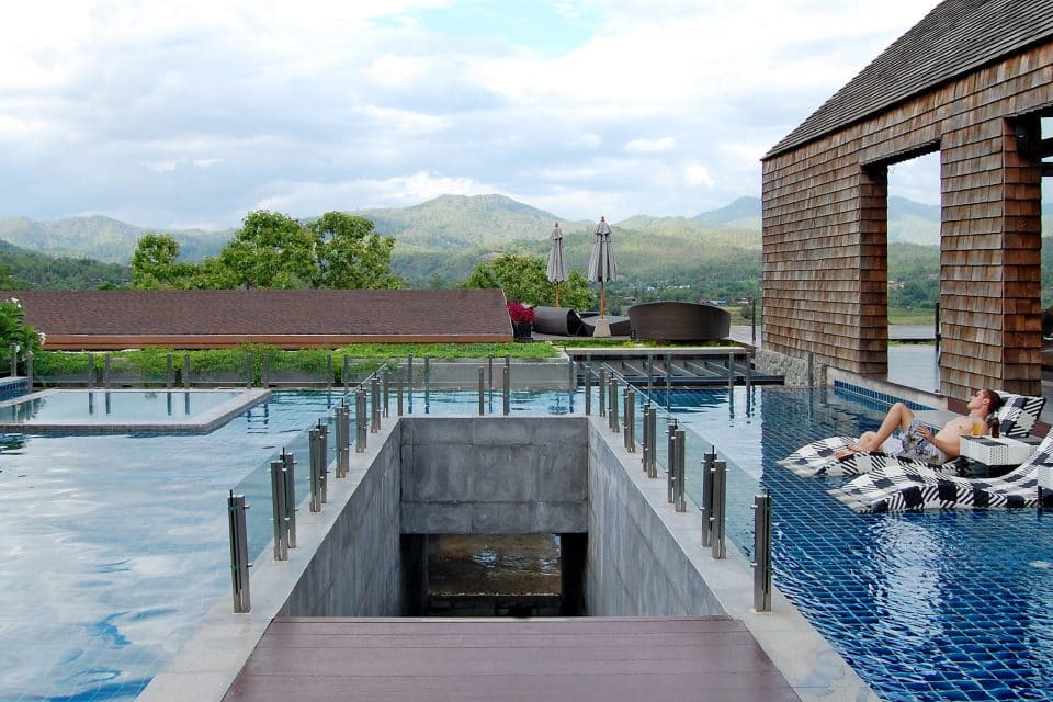 Man sits by hotel swimming pool in Pai