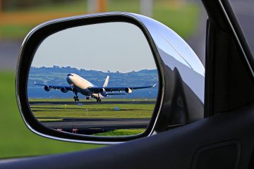 A view of a plane taking off in a car's side mirror