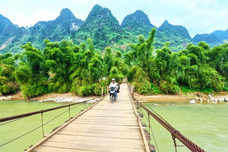 A man riding a motorbike over a wooden bridge