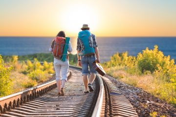 A couple backpacking down a train track