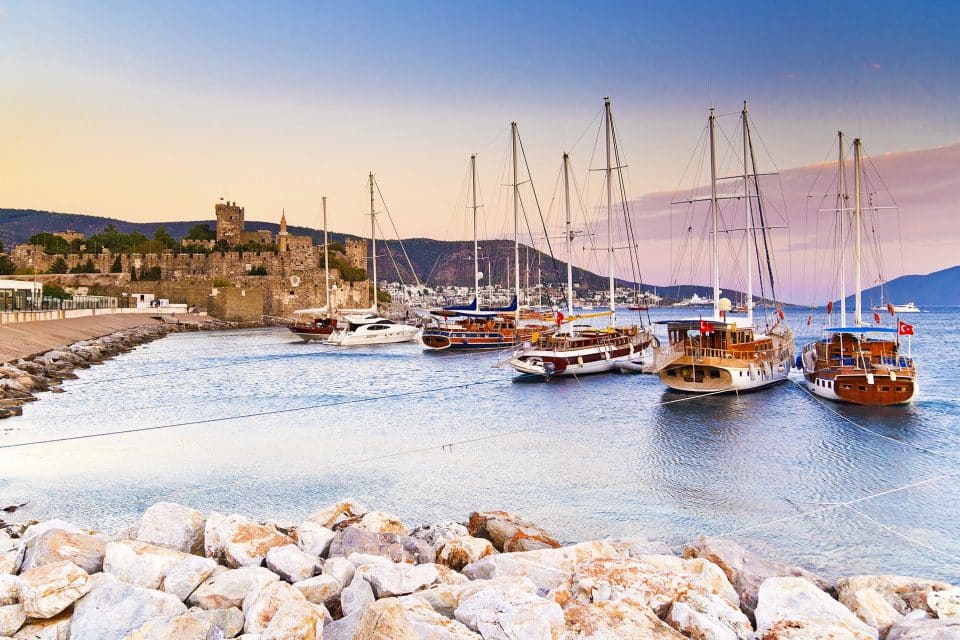 Boats anchored in the sea next to a castle