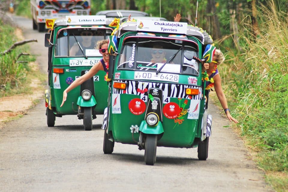 Two girls hang out of a tuk tuk on the Lanka Challenge