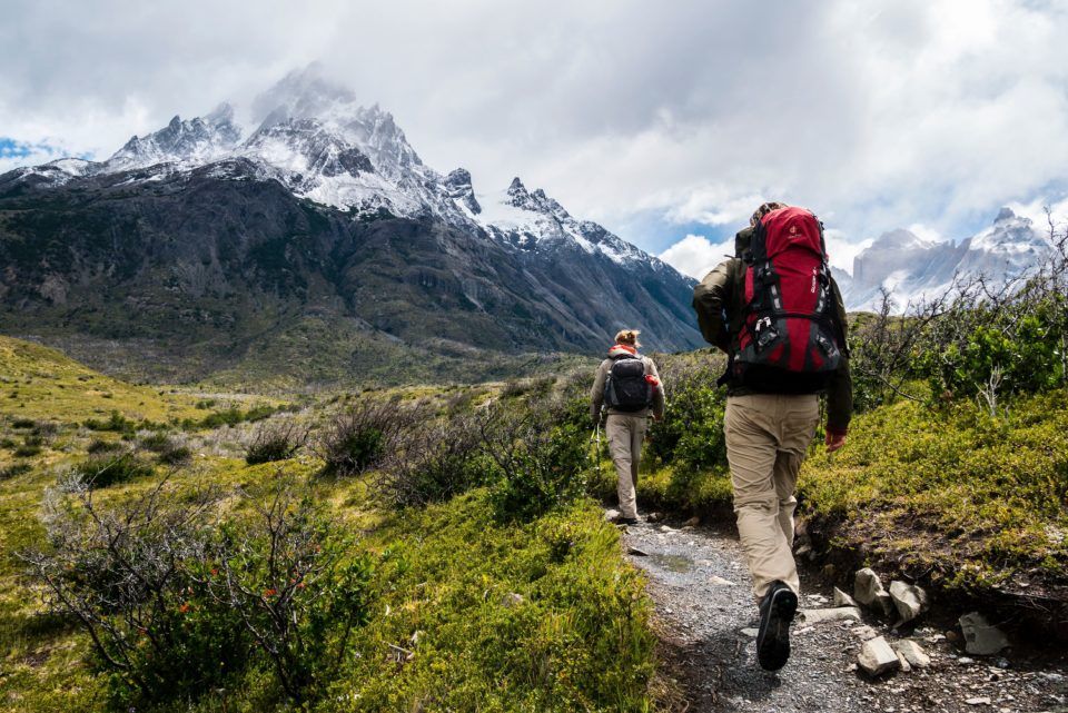 Man hiking a trail in mountains wearing backpack
