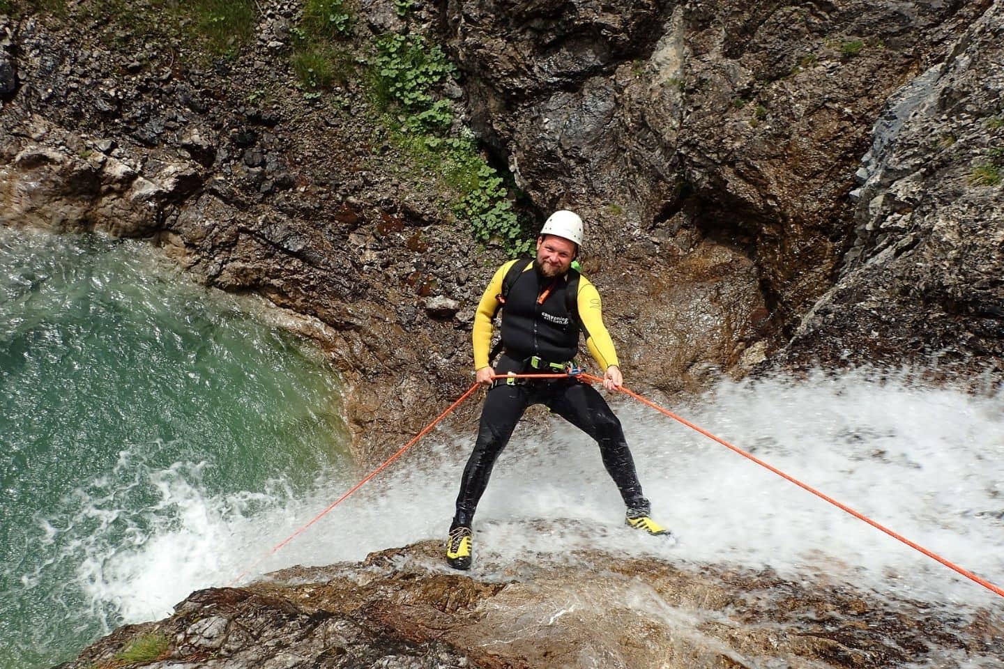 man canyoning down a waterfall