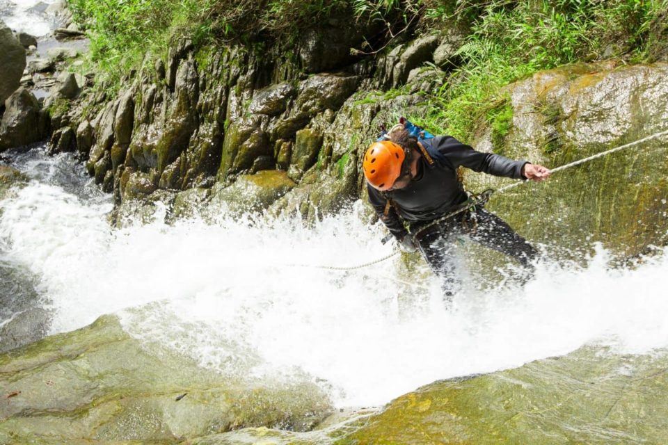 man canyoning down waterfalls