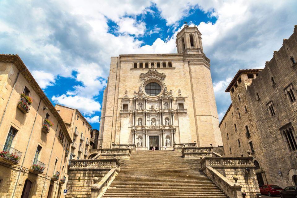 steps leading up to large stone cathedral with blue sky and clouds behind