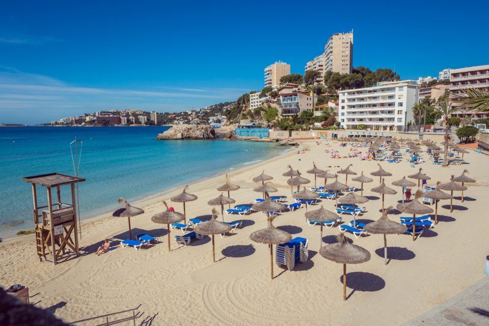 beach with buildings behind and umbrellas and young chairs