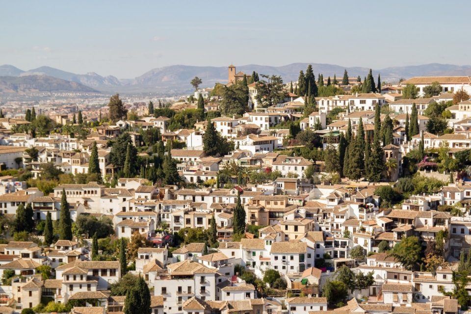 white washed buildings sitting between trees on a hill