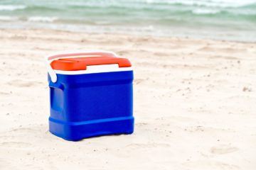 Blue hard sided cooler on the shore