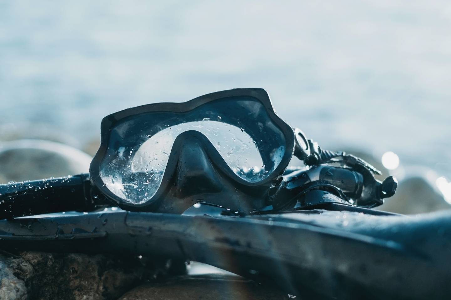 Equipment of freediver on pebble coast near the sea, mask and flippers with snorkel