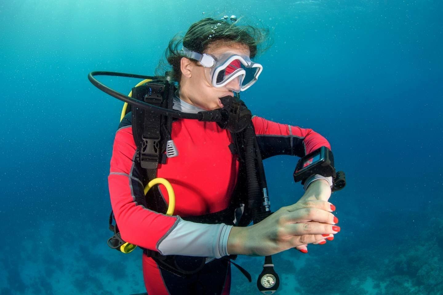 Scuba diver girl looking at her dive computer during the dive.